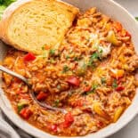 Stuffed pepper soup with bread in white bowl with spoon.