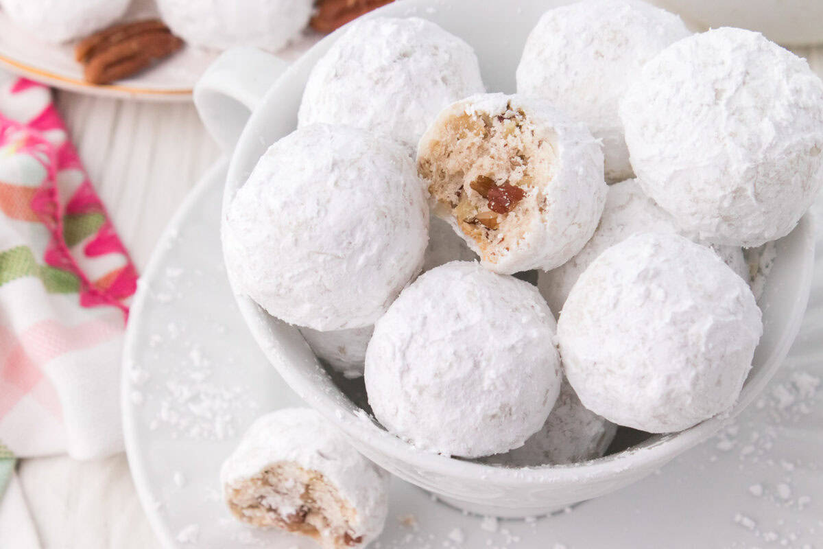 Bowl of snowball cookies with bite taken out.