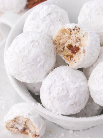 Bowl of snowball cookies with bite taken out.