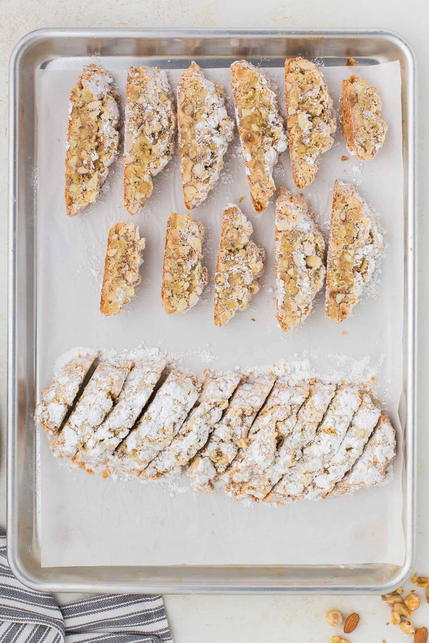 Biscotti cut on one side and log that is sliced on another on tray. 