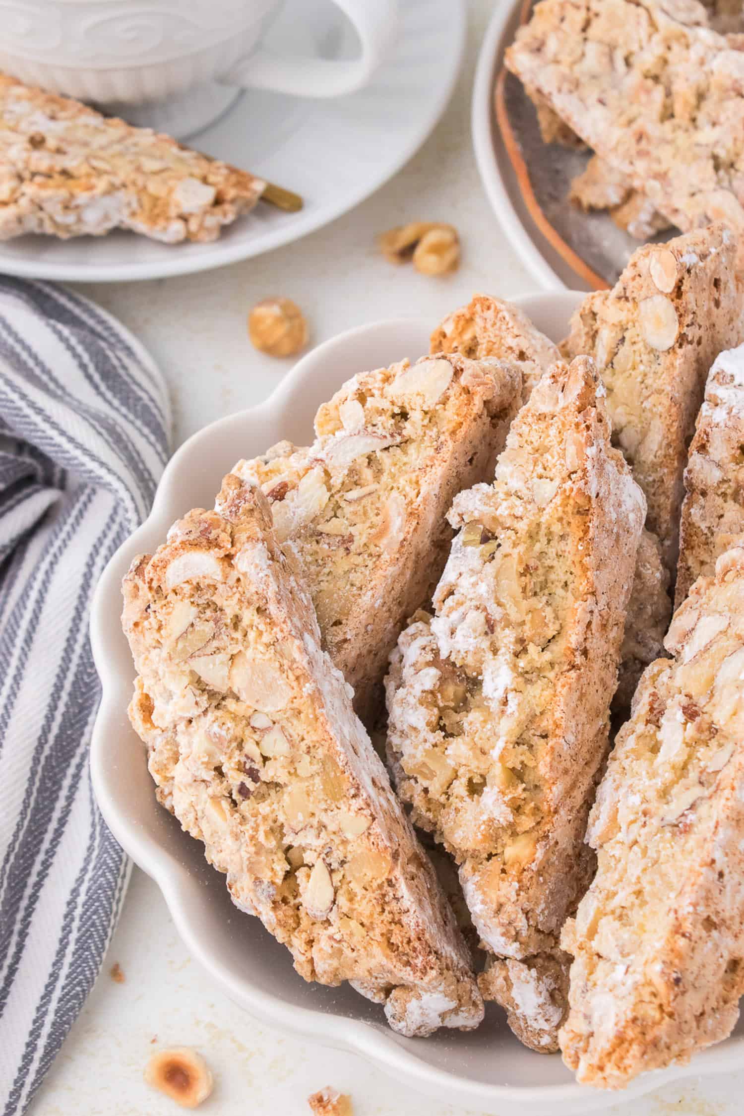 Italian nut biscotti on white scalloped dish. 