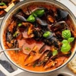 Mussels Red in a large white pot garnished with basil.