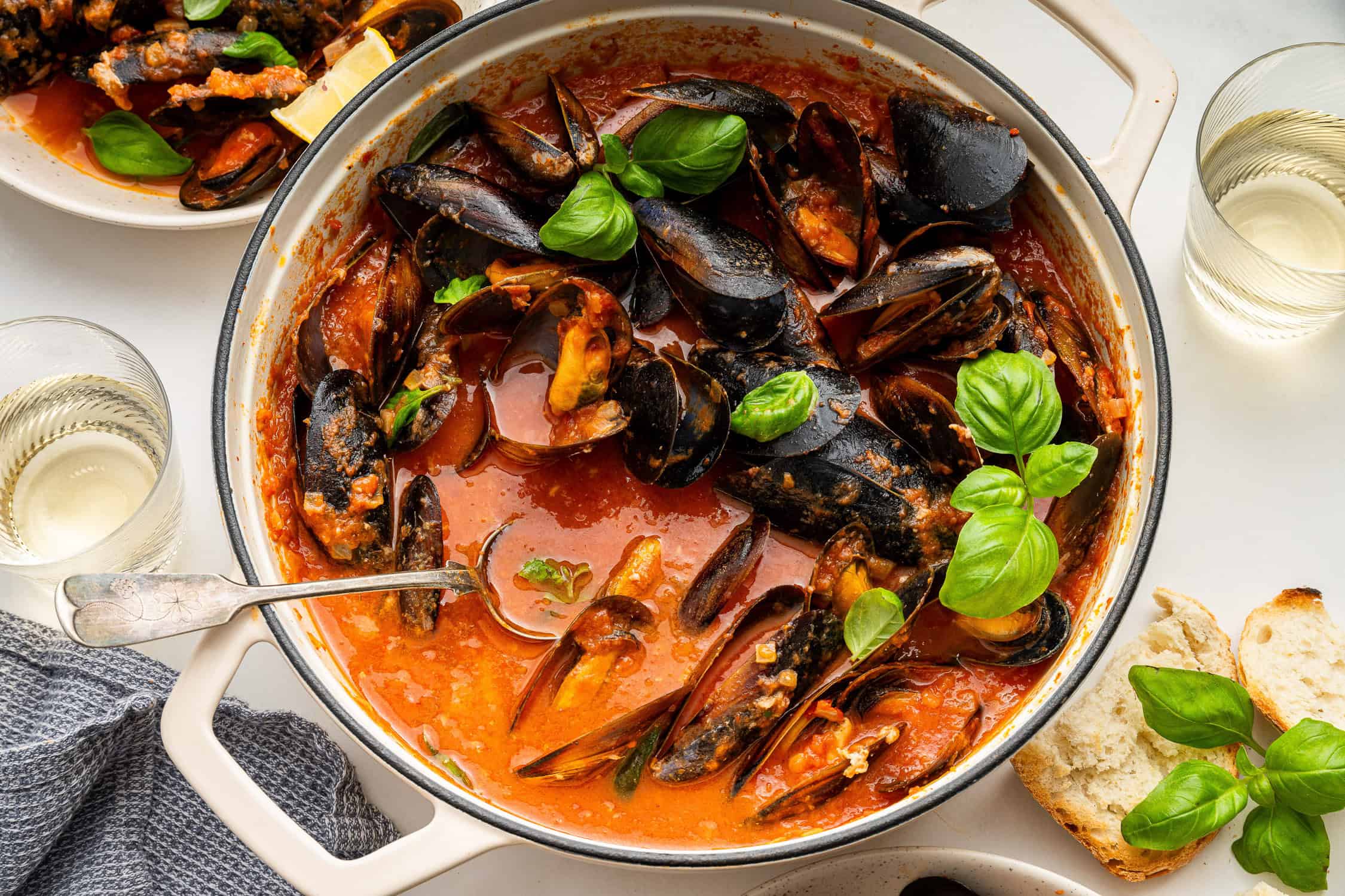 Mussels Red in a large white pot garnished with basil.