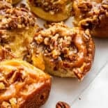 Sticky buns with nuts and cinnamon sticks on side.