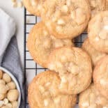 White chocolate macadamia nut cookies on wire reach with bowl of nuts.