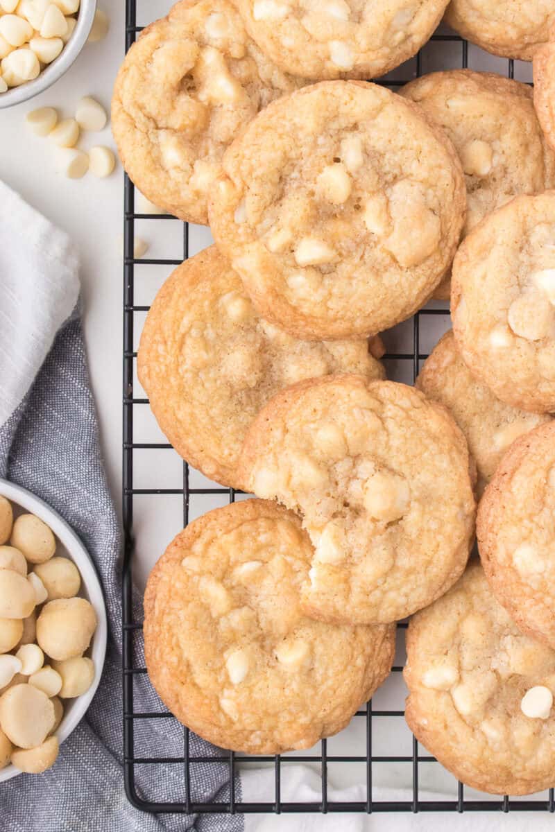 White chocolate macadamia nut cookies on wire reach with bowl of nuts.