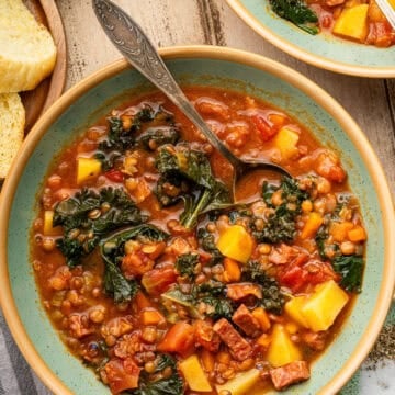 Lentil and Sausage soup in bowl with spoon.