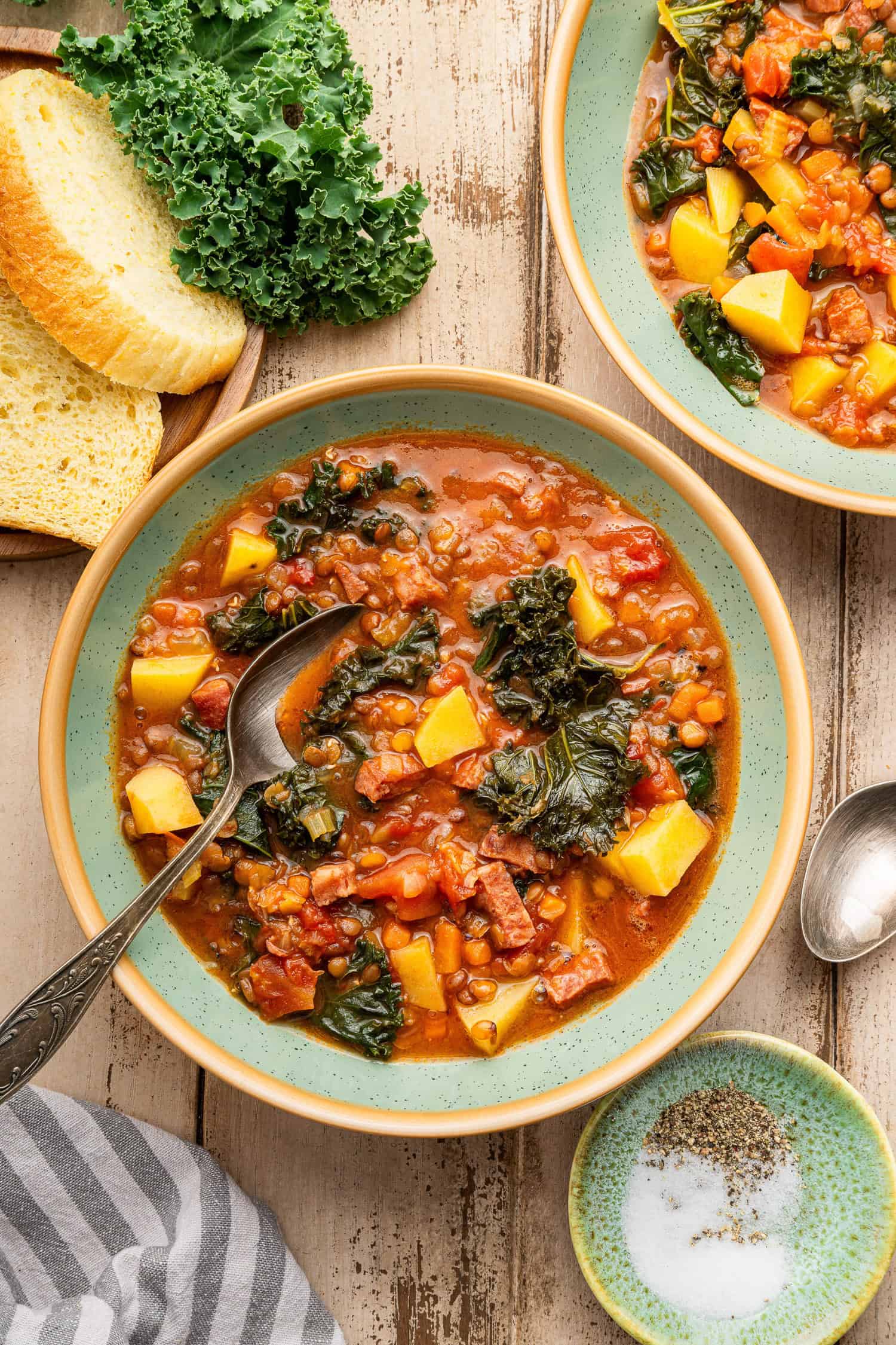 Sausage and lentil soup in bowl with spoon. 