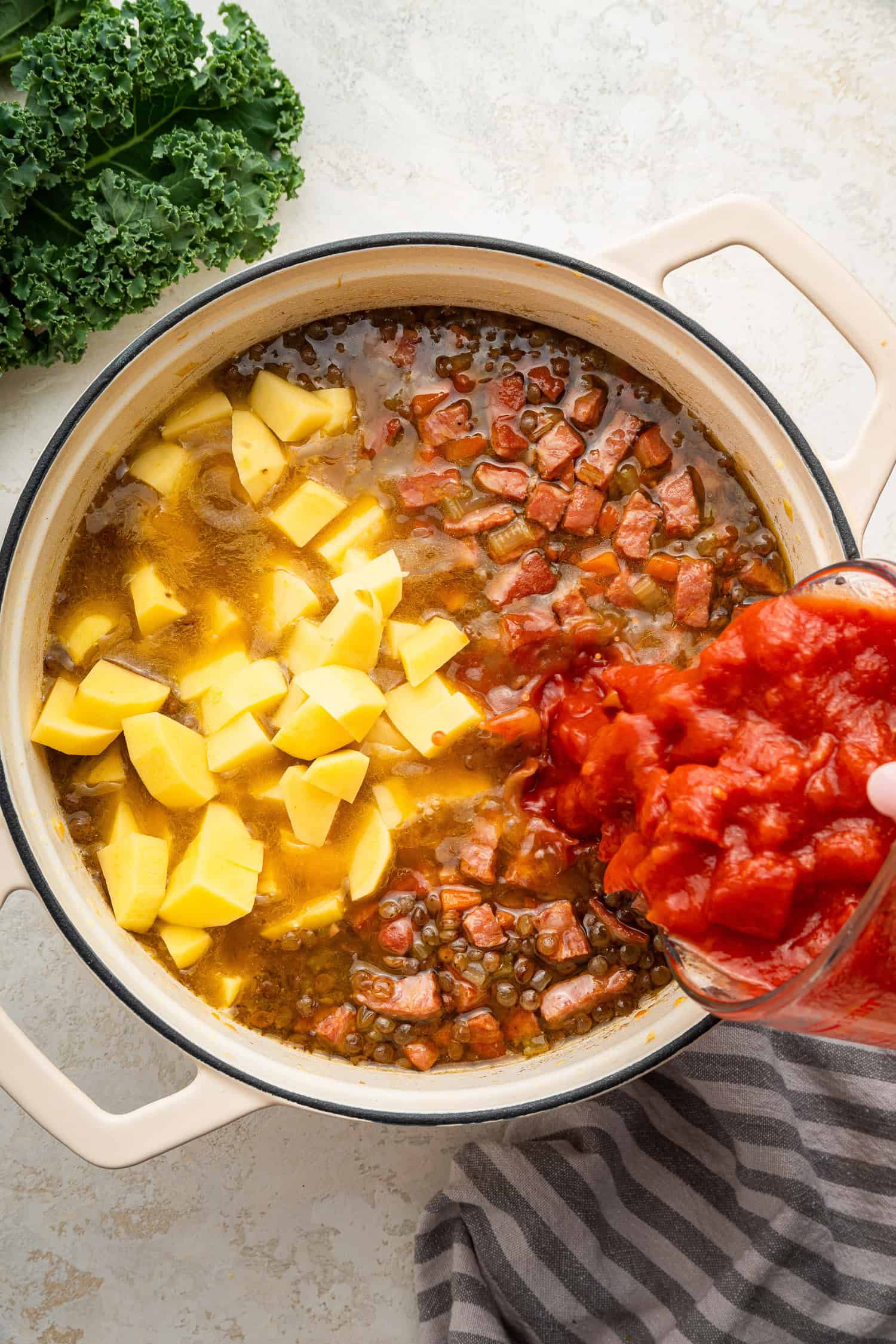 Adding tomatoes and potatoes to pot for soup. 