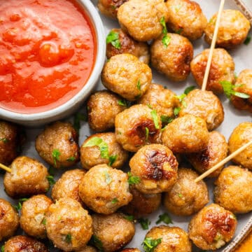 Plate of mini meatballs with dish of tomato sauce.