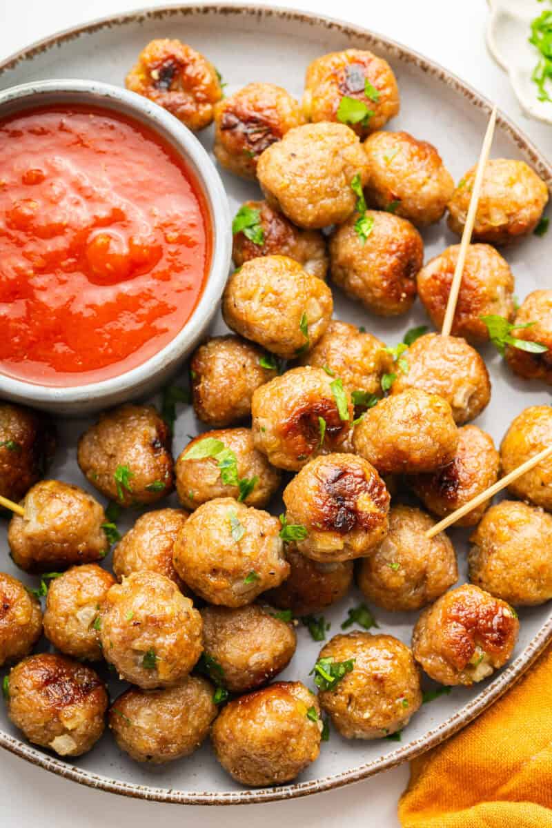 Plate of mini meatballs with dish of tomato sauce.