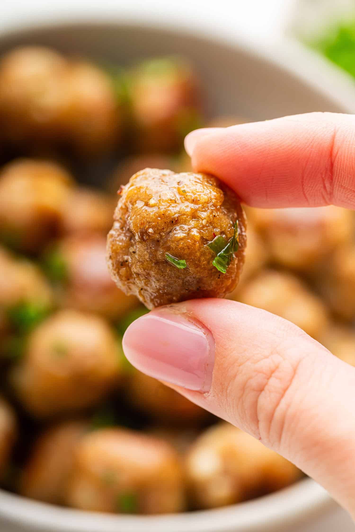 Hand holding a close-up of a mini meatball. 