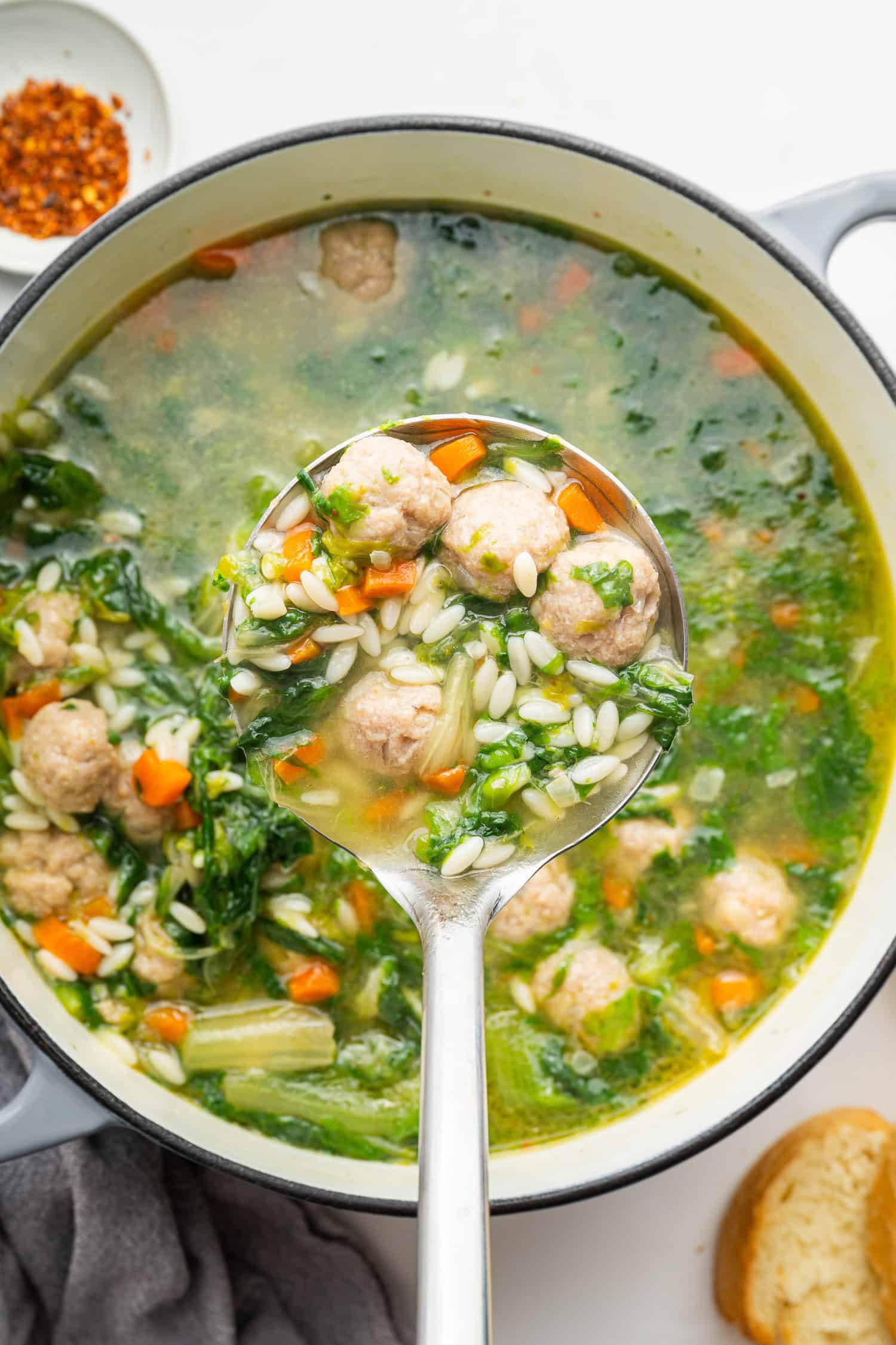 Pot of Italian Wedding Soup with large spoonful on top. 