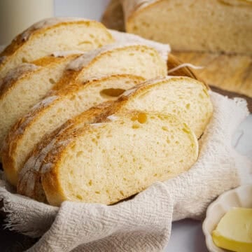 Sliced homemade Italian bread in basket with cloth.