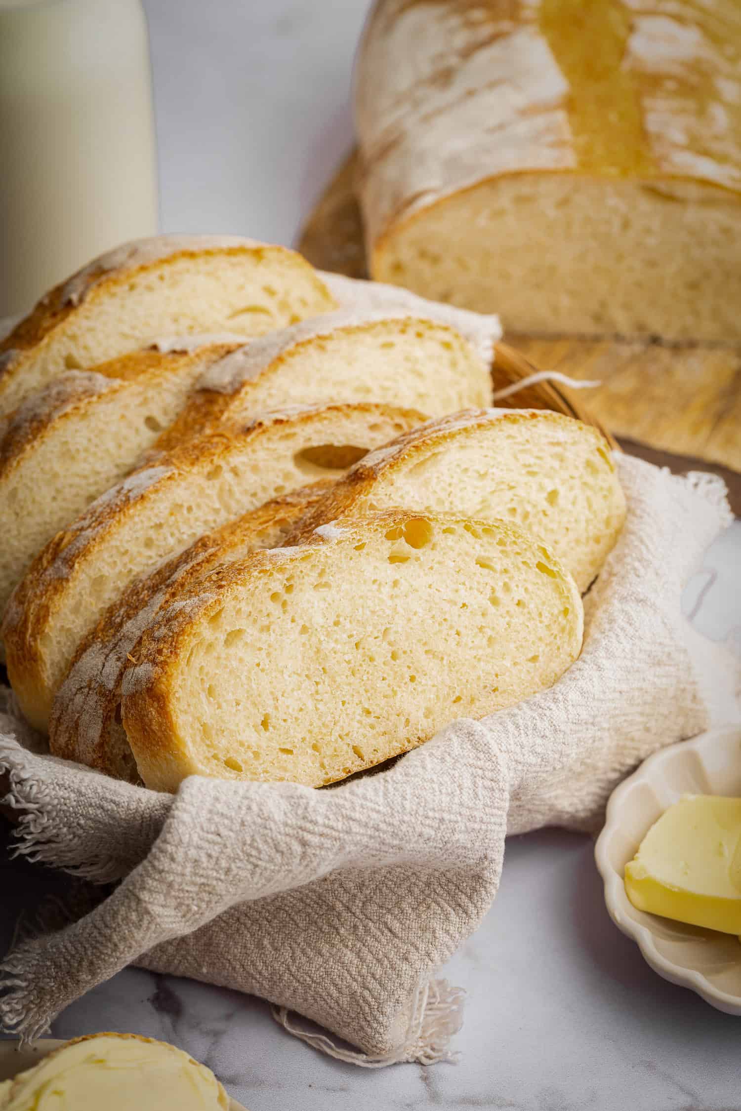 Sliced homemade Italian bread in basket with cloth. 