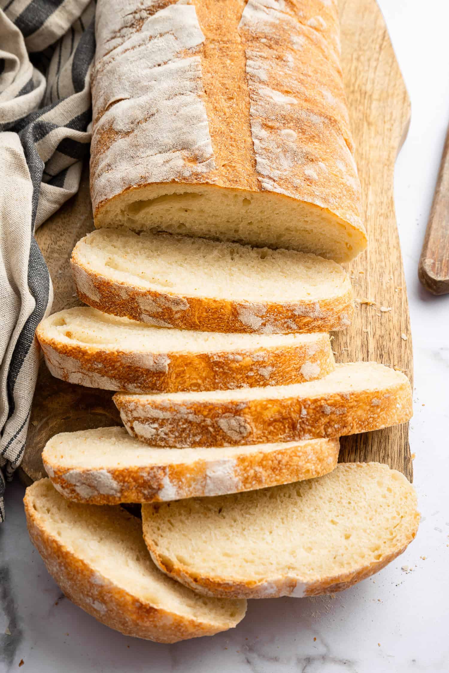 Sliced Italian bread on wooden board. 