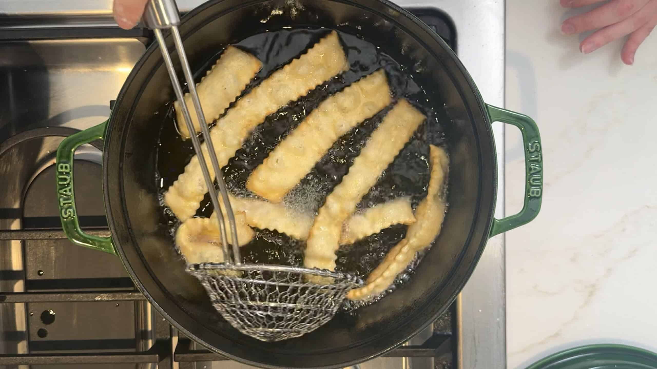 Frying crostoli in pot of oil. 