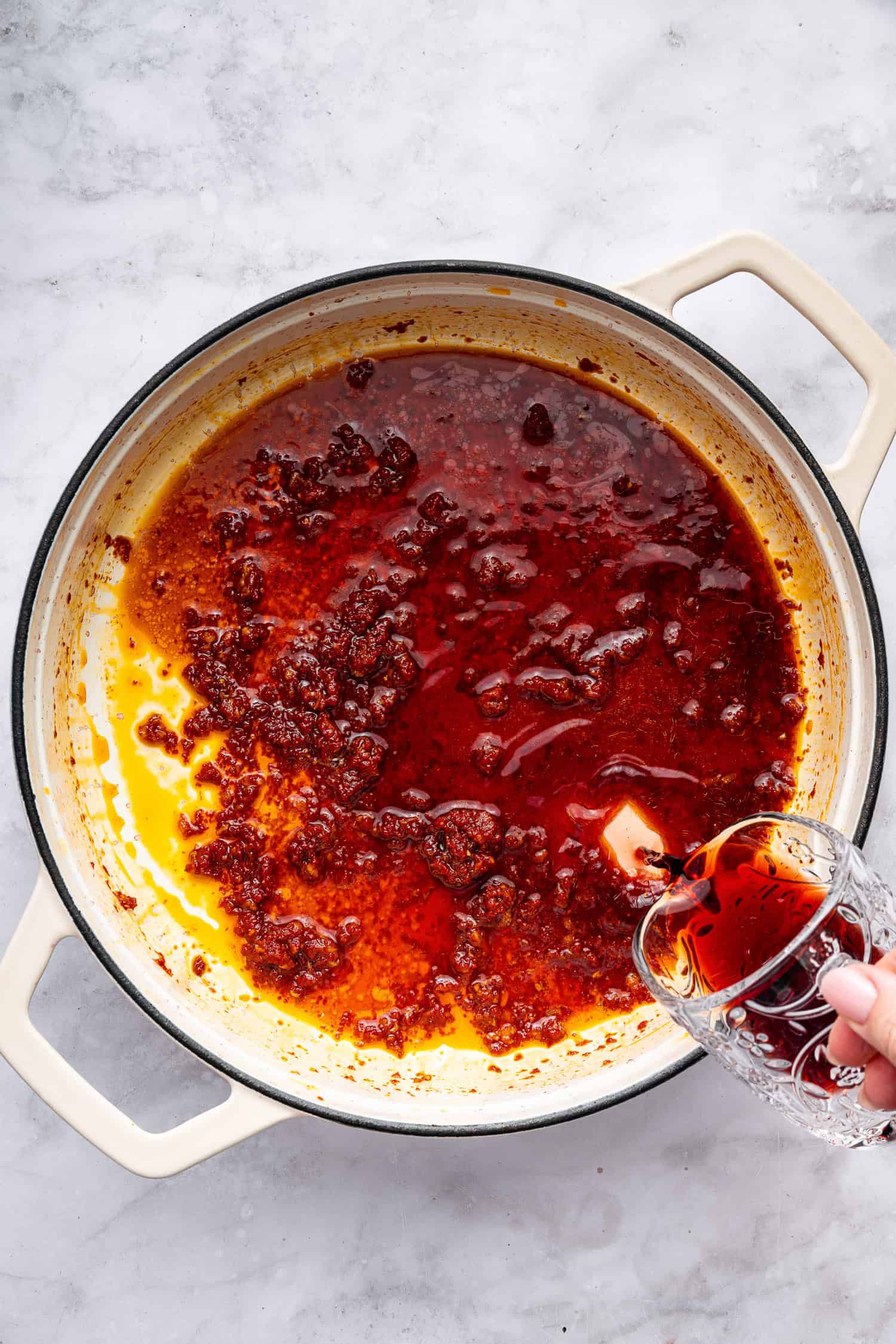 Adding red wine to tomato paste and seasonings. 
