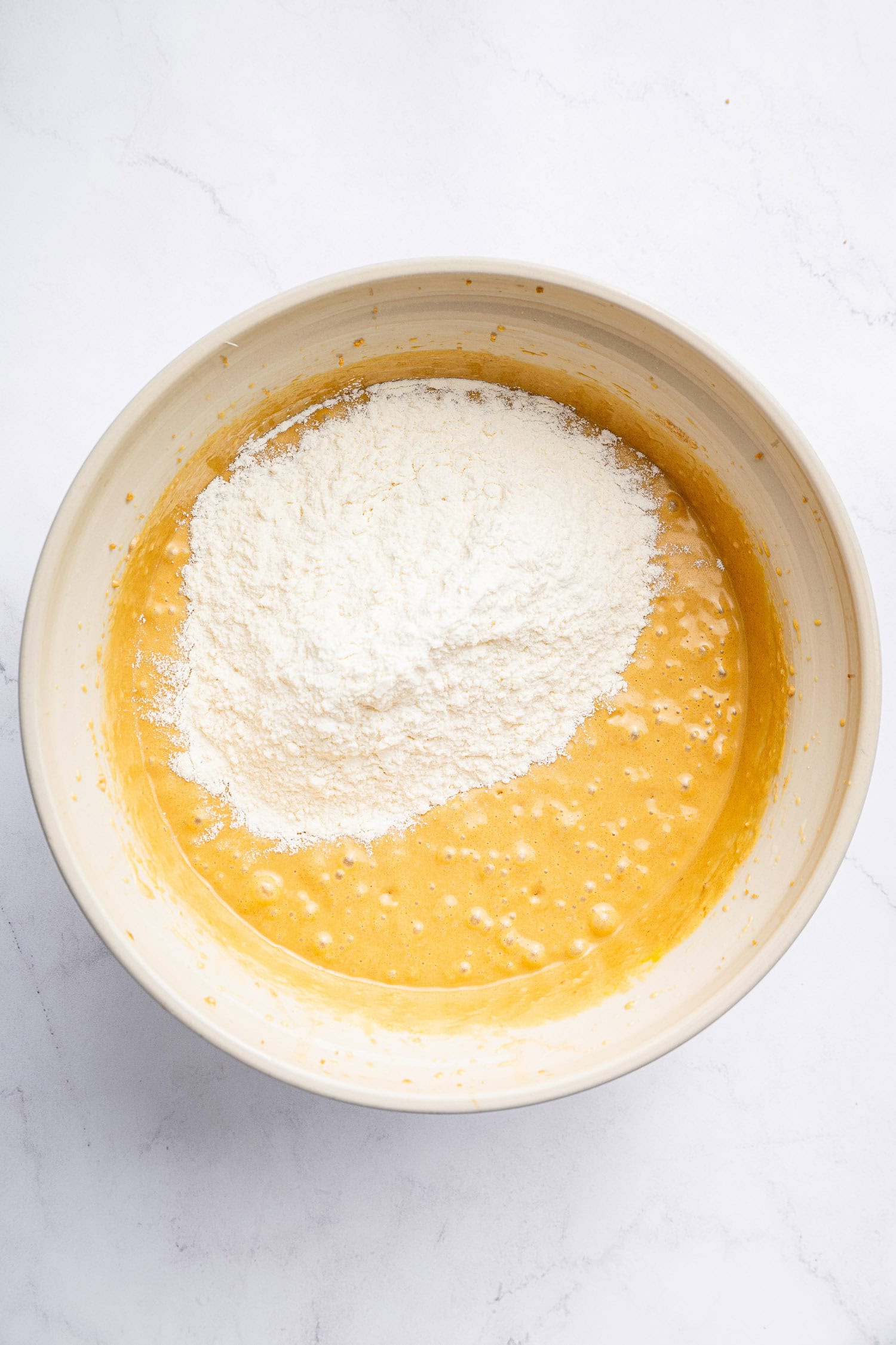Adding flour to cake batter in large bowl.