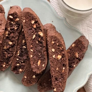 Chewy chocolate biscotti with chopped nuts served on a decorative plate.