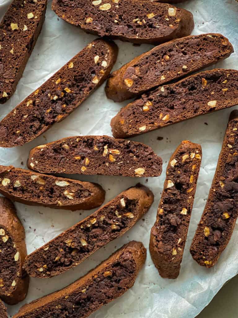 Rich chocolate biscotti with chopped nuts on parchment paper.