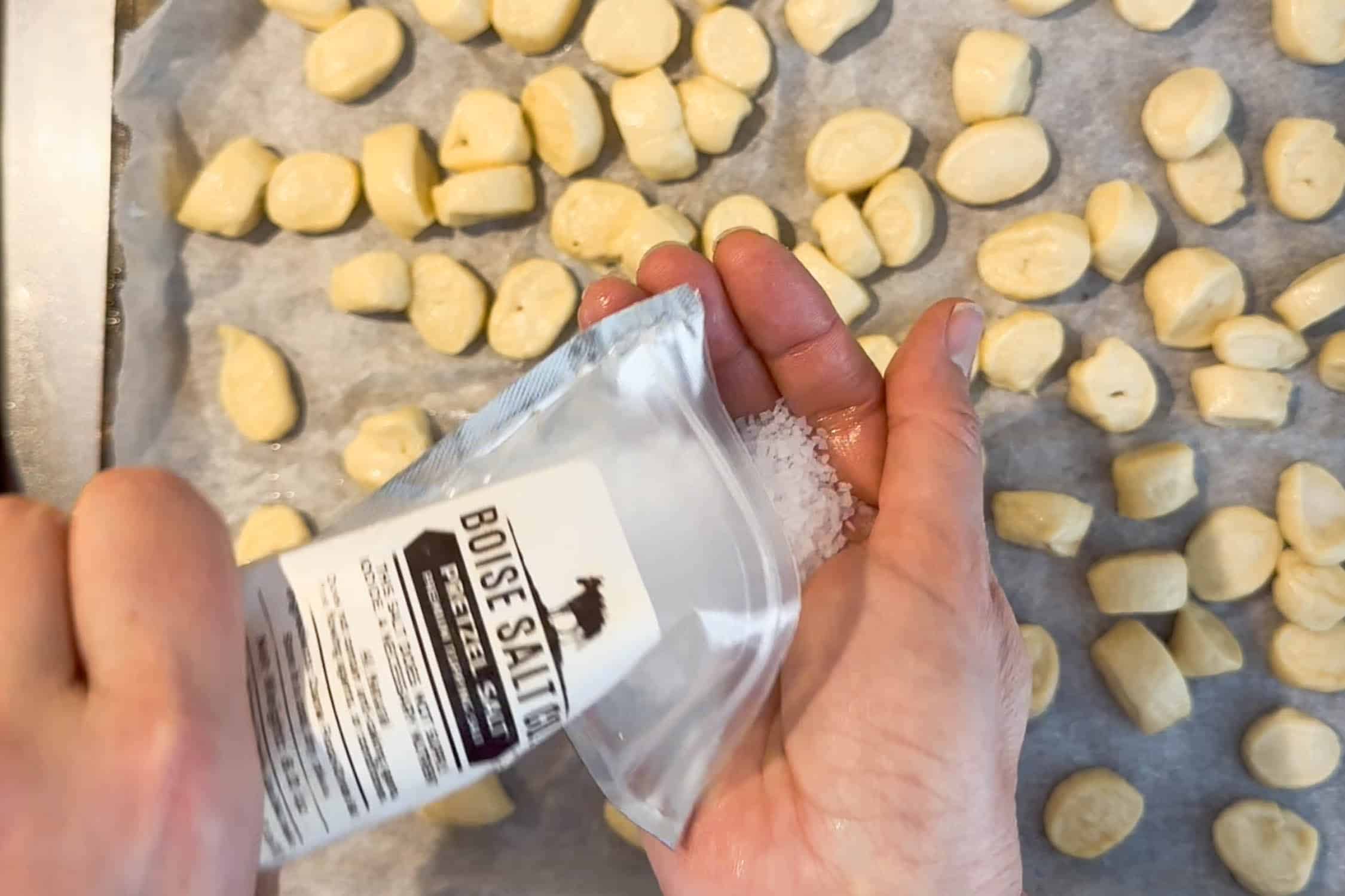 Adding pretzel salt to pretzel bites before baking.