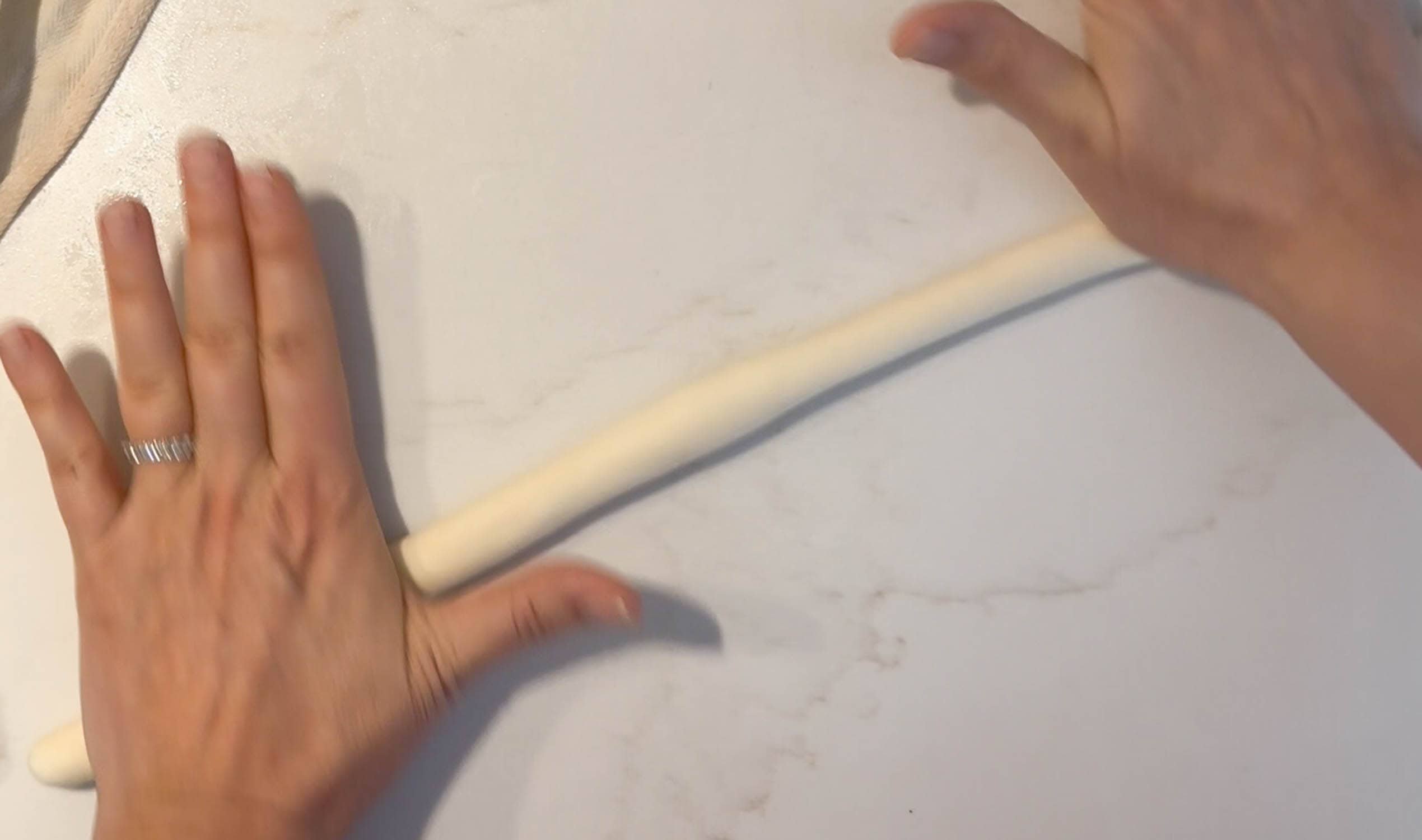 Rolling out pretzel dough into long ropes.