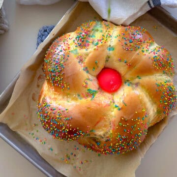 Loaf of italian easter bread with pink egg and sprinkles.