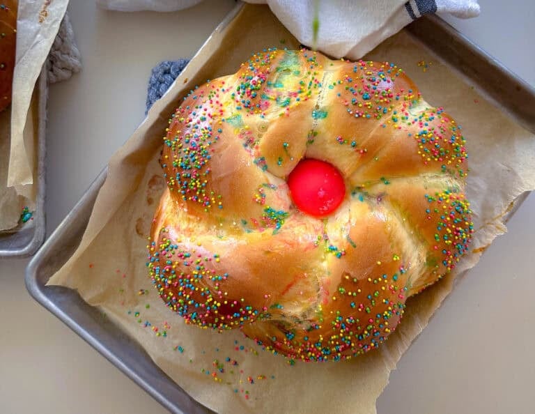Loaf of italian easter bread with pink egg and sprinkles.