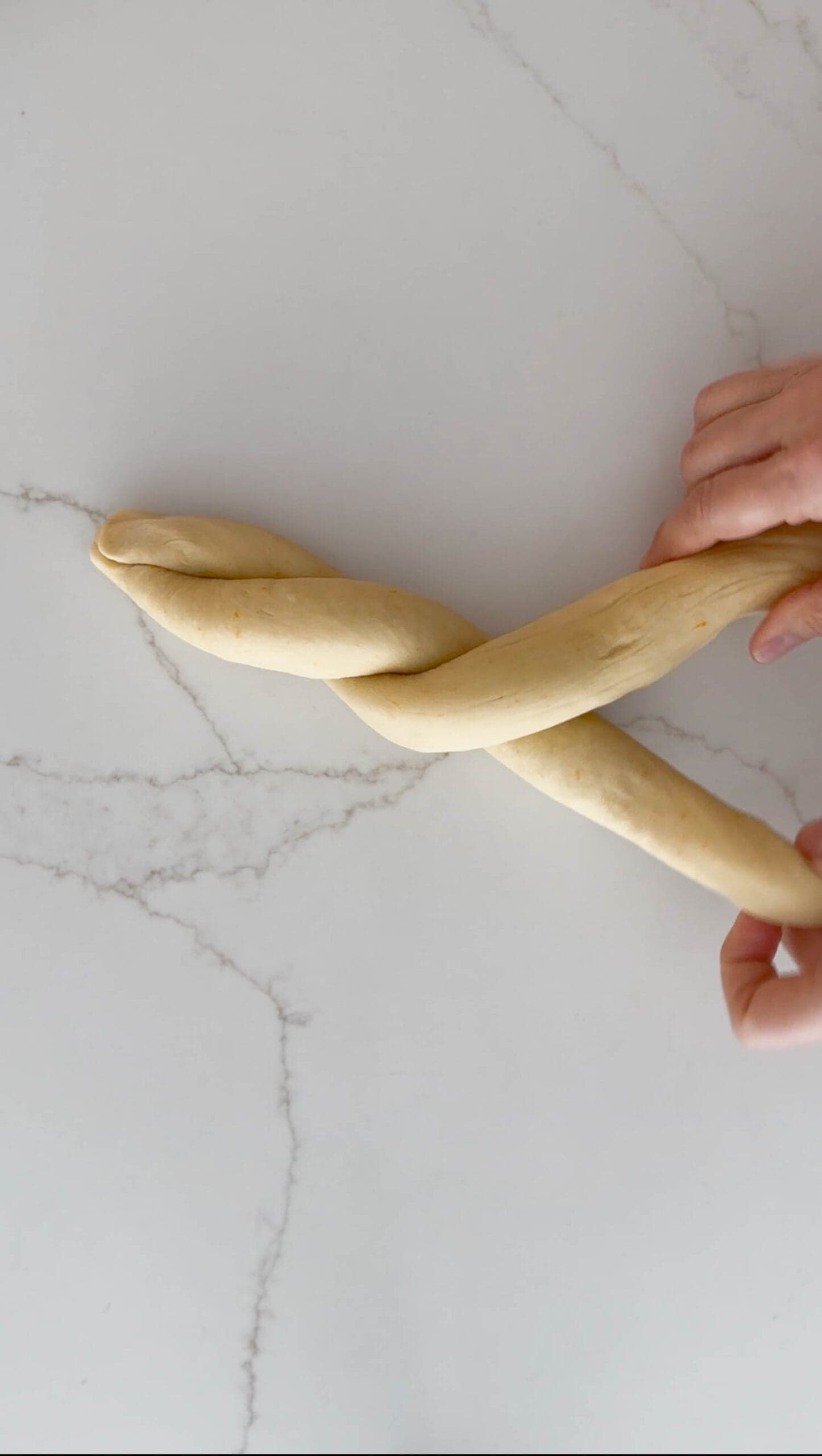 Twisting two ropes of easter bread dough. 