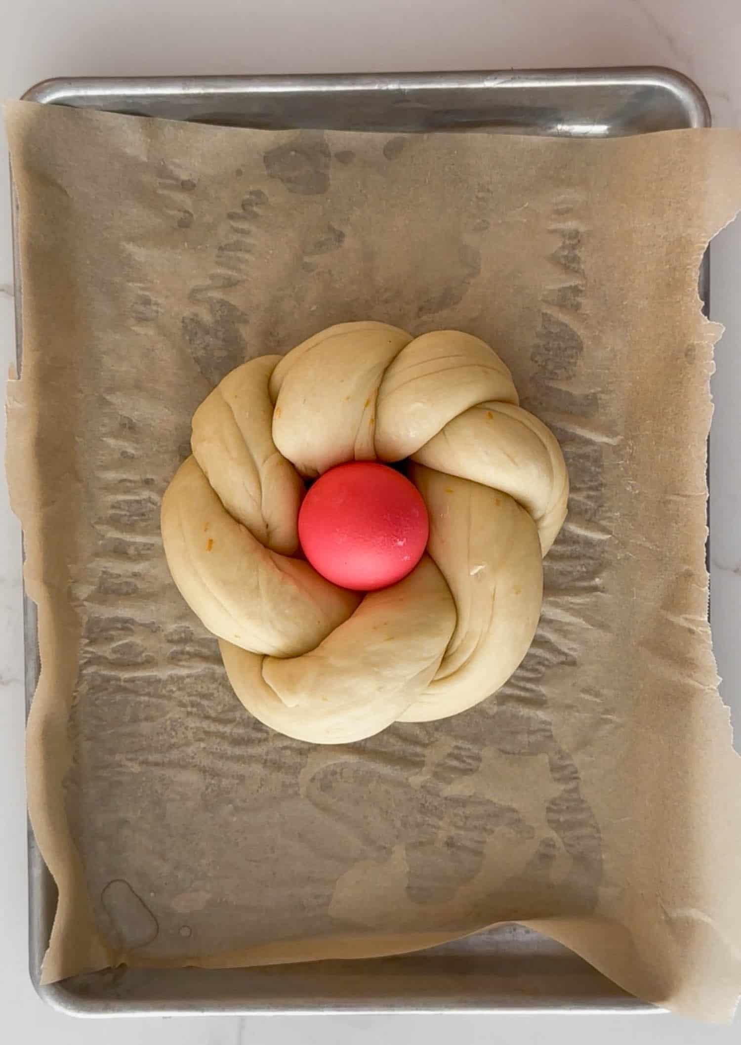 Unbaked loaf of easter bread on parchment lined sheet. 
