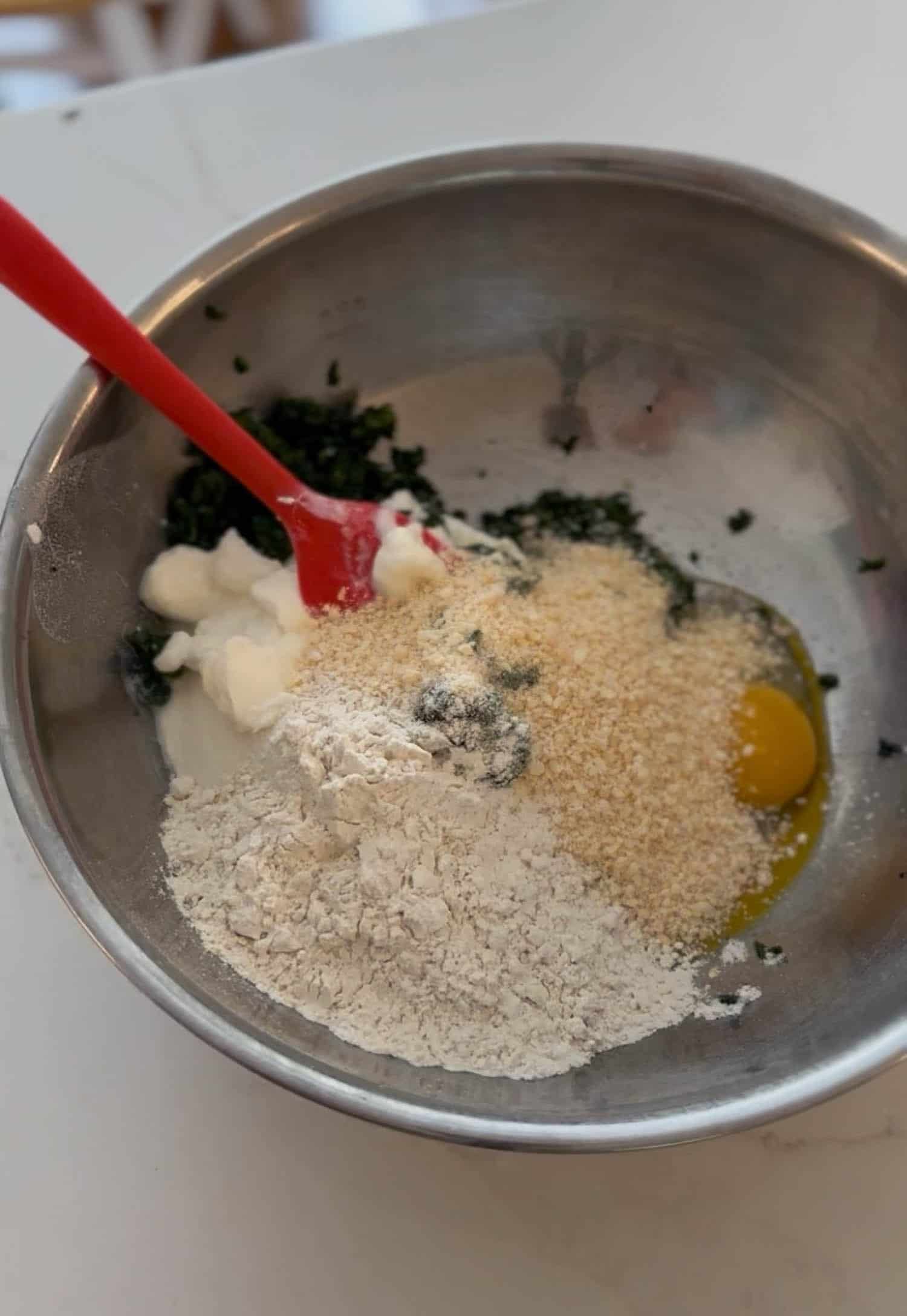 Ingredients for gnudi in large silver mixing bowl.