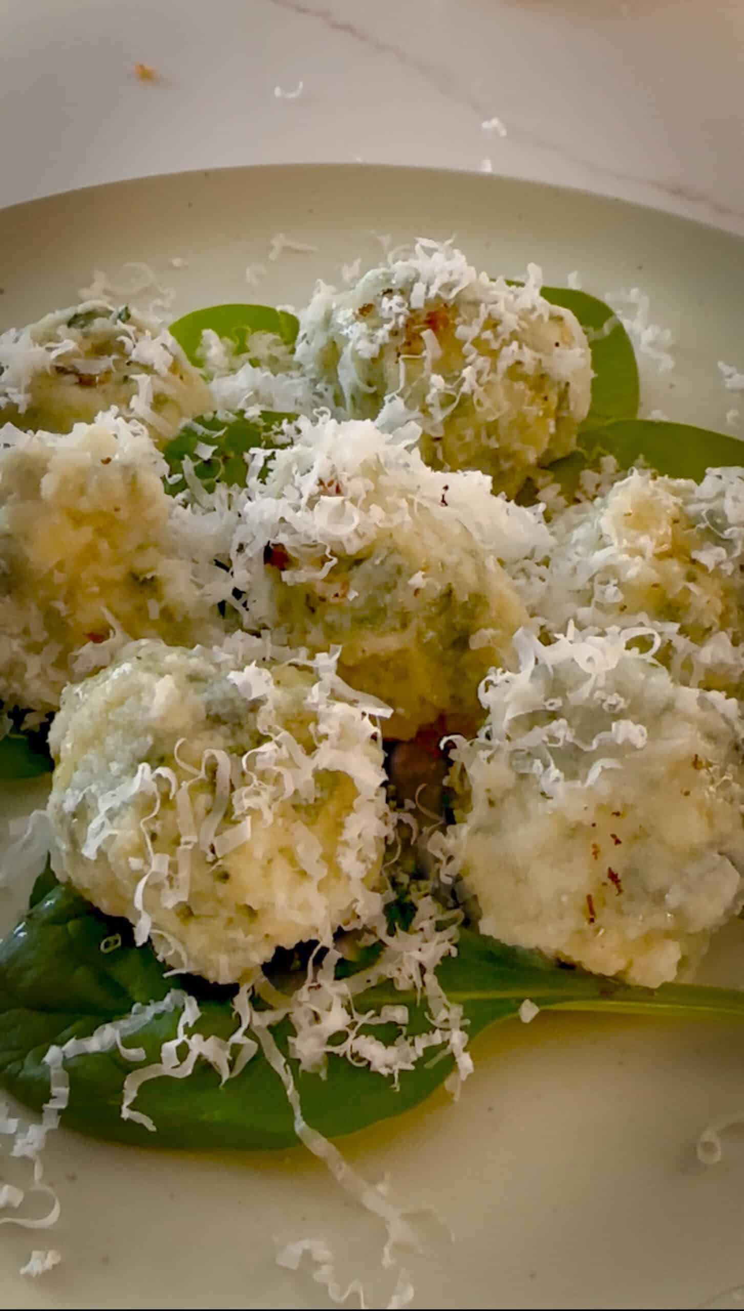 Close up of gnudi with lots of grated cheese.
