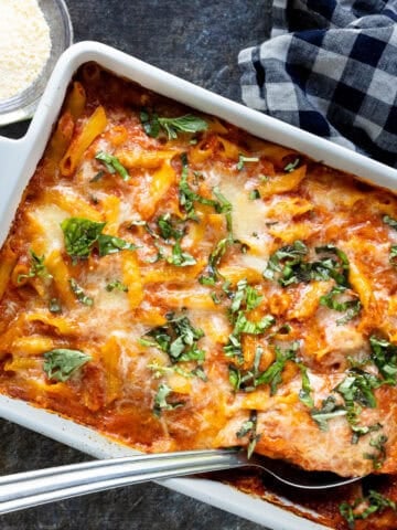 Overhead view of baked ziti in white baking dish.
