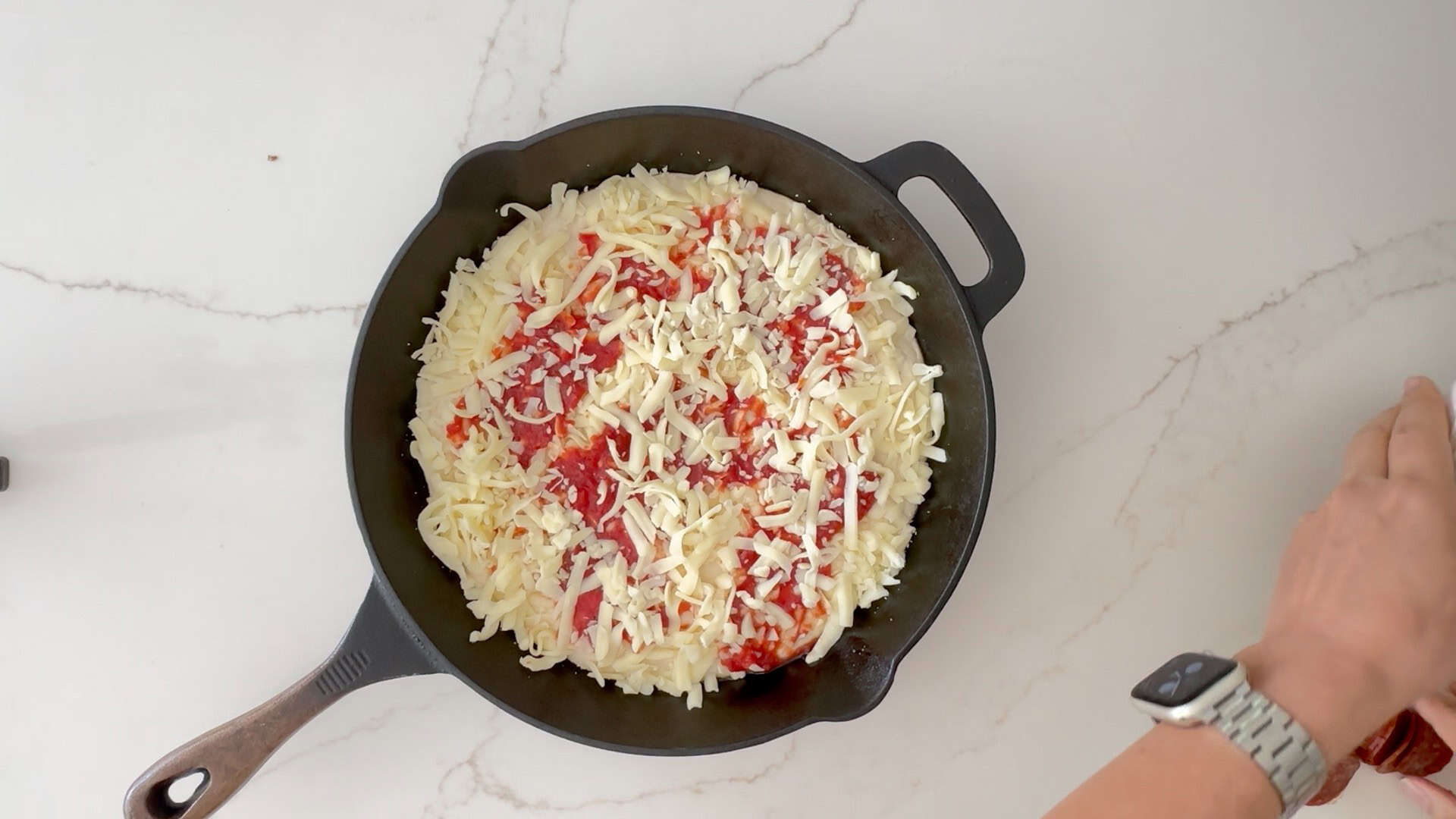 Adding cheese and sauce to pizza. 