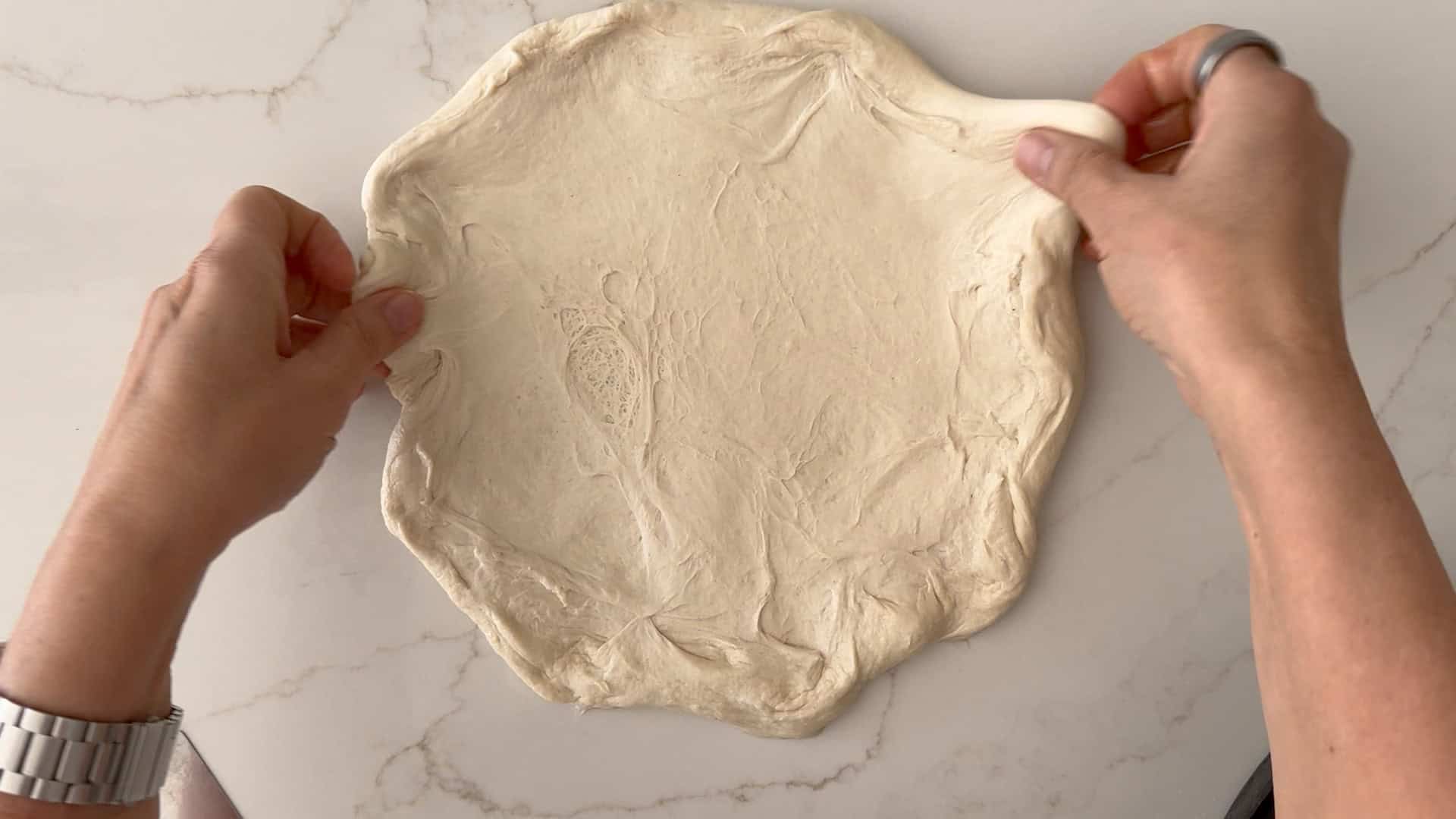 stretching the dough on the counter. 