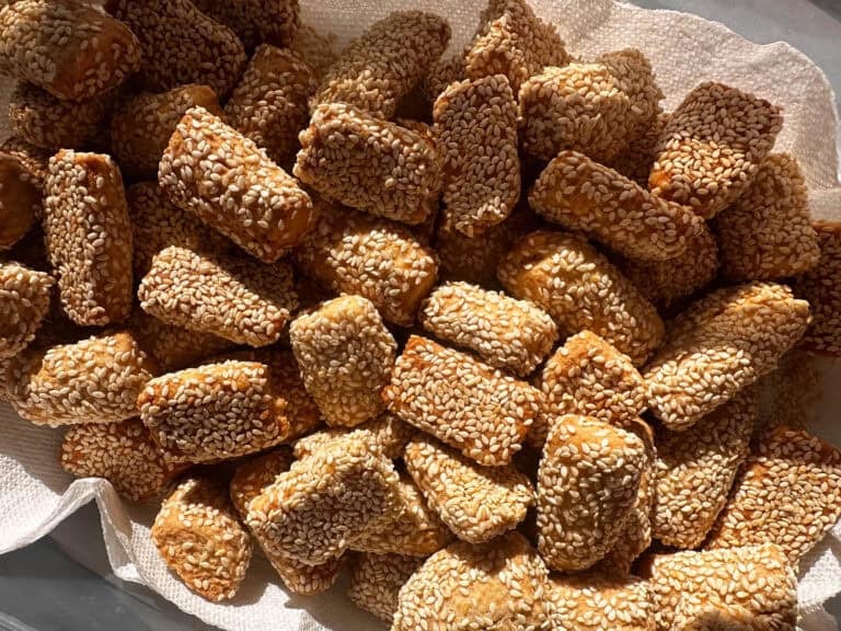 Italian sesame cookies on baking tray lined with parchment.